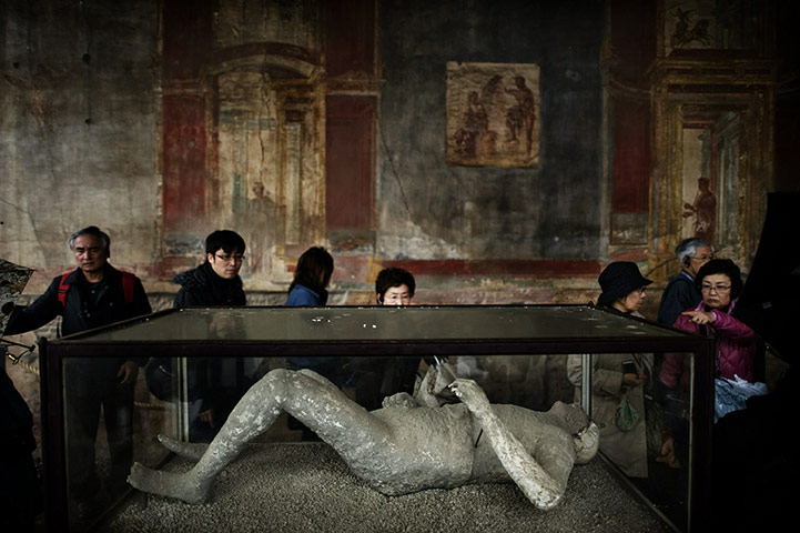 24 hours in pictures: Tourists look at a body cast at archeological site of Pompeii