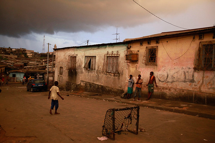 24 hours in pictures: Boys watch a street soccer game as a storm looms, Ivory Coast