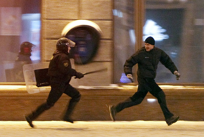 Belarus election violence: A riot policeman chases an opposition protester during a rally