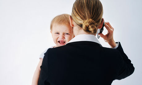 Businesswoman on her mobile phone carrying a baby