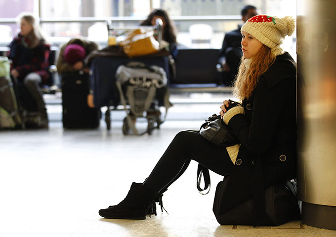 Travel Chaos: A girl sits on her bag as she waits for her flight at Edinburgh Airport