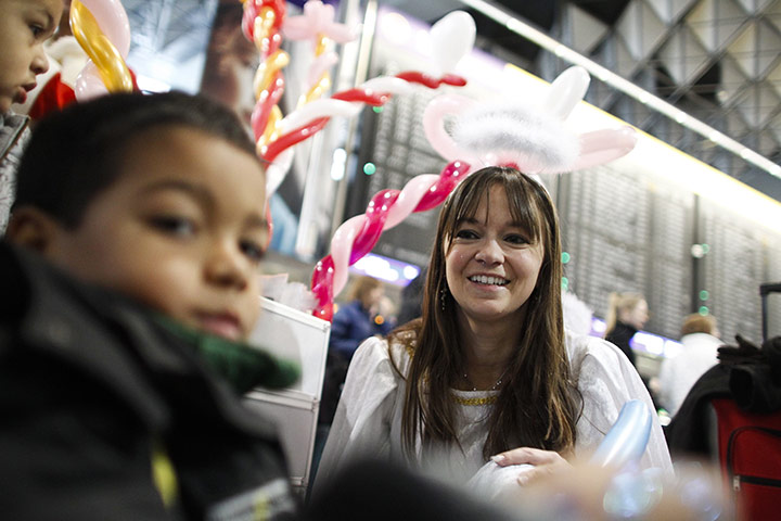 Travel Chaos: An airport employee dressed as an angel entertains children