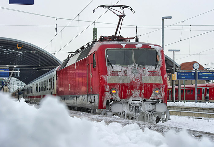 Travel Chaos: A train covered with ice and snow leaves the train station of Halle