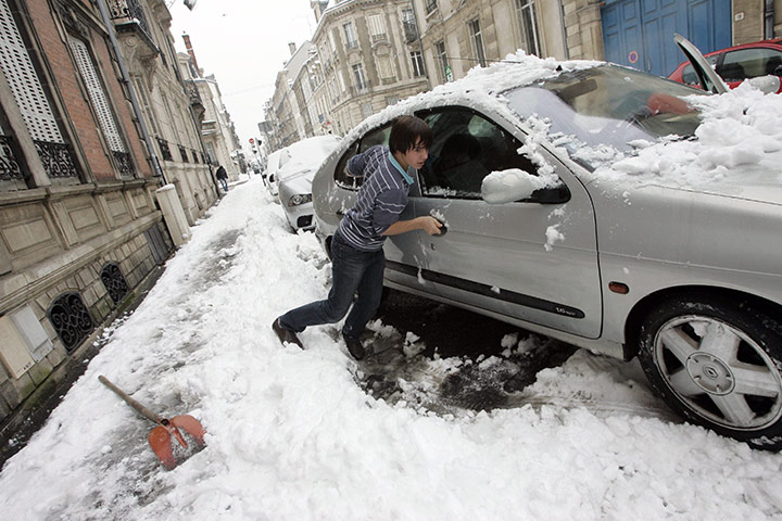 Travel Chaos: A volunteer tries to push a car blocked by the snow in a street