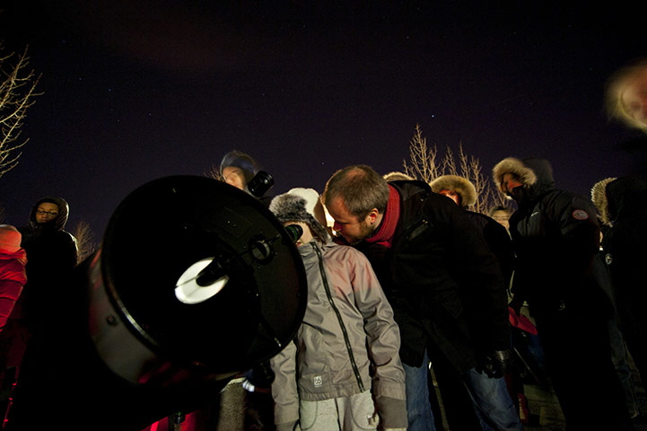 Lunar Eclipse: On a Reykjavik parking lot people gather around a telescope