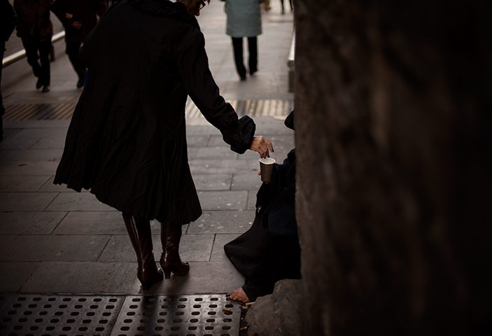 24 hours in pictures: A woman gives money to a beggar in Barcelona 