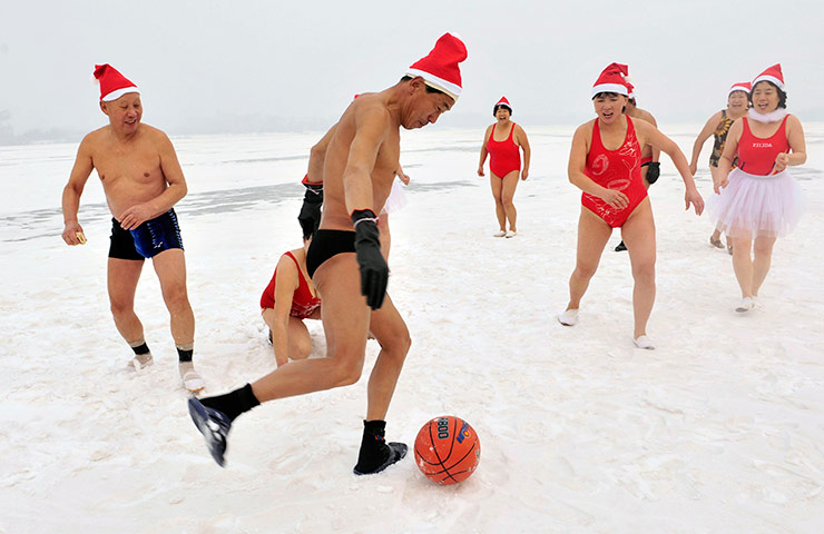 24 hours in pictures: Swimmers wearing Santa Claus hats, play with a ball on a snow covered river