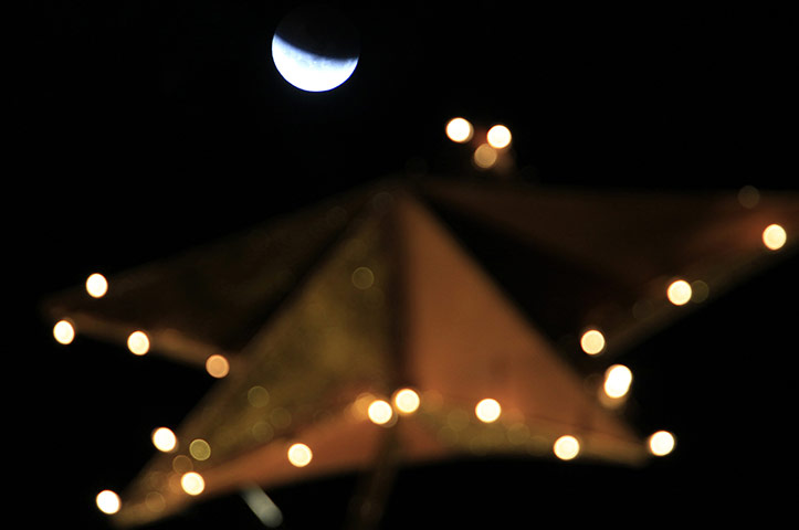 Lunar Eclipse: The Moon is seen over a Christmas tree during a total lunar eclipse