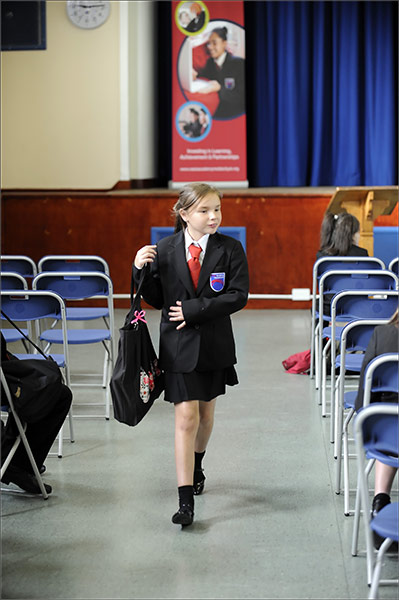 School Uniforms: A schoolgirl walks through an assembly hall in smart uniform