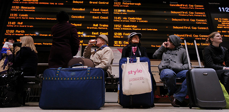 Travel Chaos: Passengers sit underneath an electronic information board