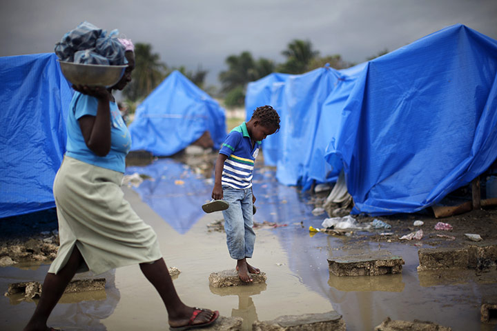 2010 year in MDG: A boy crosses a puddle of water after heavy rains  in Port-au-Prince