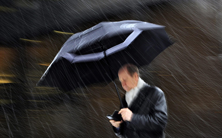 Week in Business: A man with an umbrella walks during a snowfall in London 