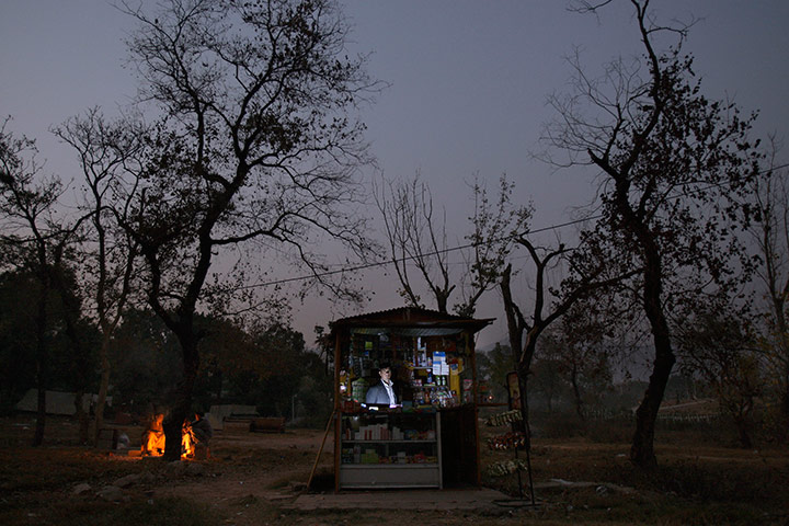 24 hours in pictures: A Pakistani man looks on from inside his grocery store