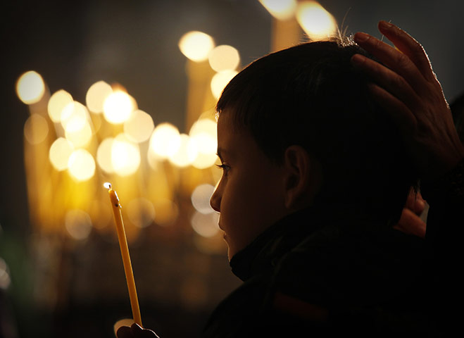 24 hours in pictures: A Bulgarian boy lights candle as he attends the Christmas Mass