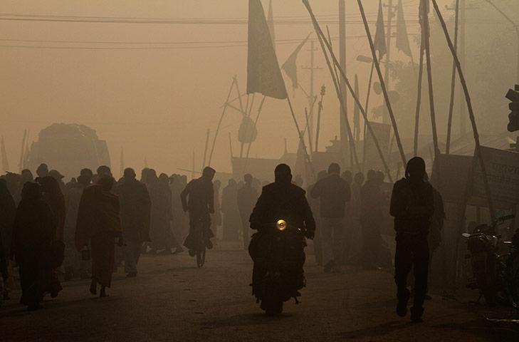 24 hours : Allahabad, India: A man on a scooter rides past Hindu devotees
