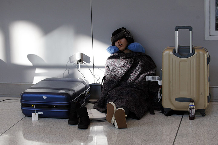 East coast blizzards: A passenger sleeps at JFK International Airport as she waits