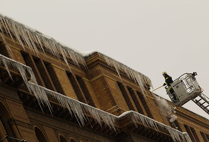 24 hours: Berlin, Germany: A fireman removes icicles from a roof 
