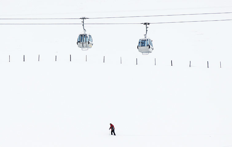 24 hours: Adelboden, Switzerland: A man walks in the snow under cable cars