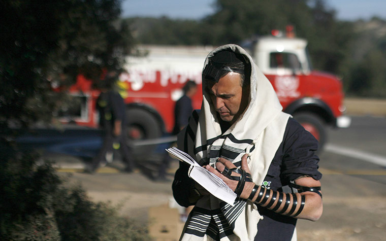 Israel Forest Fires: An Israeli firefighter prays during a forest fire in the Carmel Forest