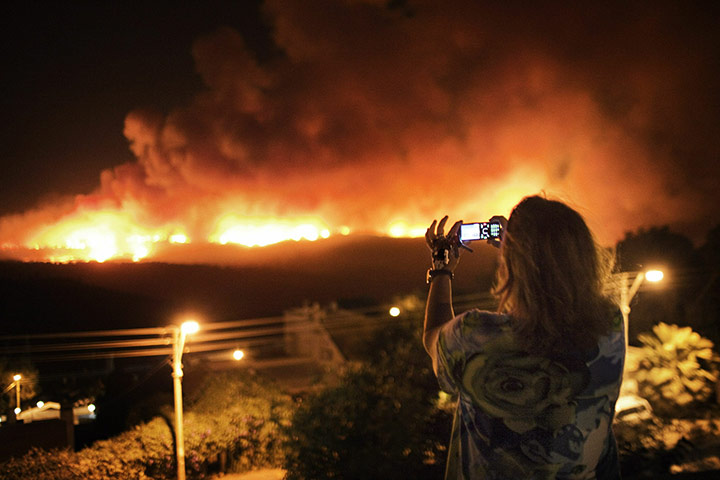 Israel Forest Fires: An Israeli woman holds the keys of her house while taking a photo of fires