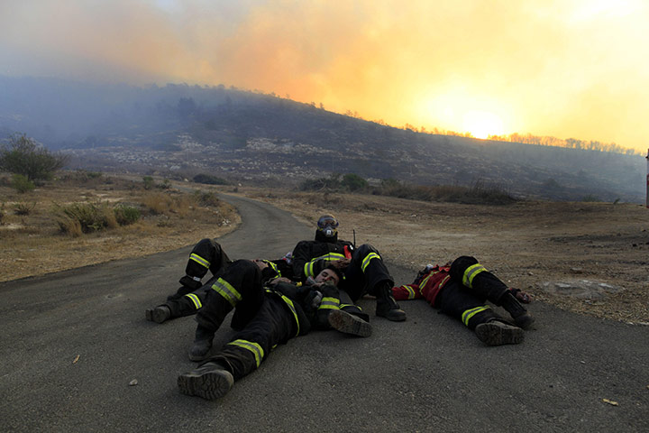Israel Forest Fires: Firefighters rest on the road at sunrise after fighting overnight Israel