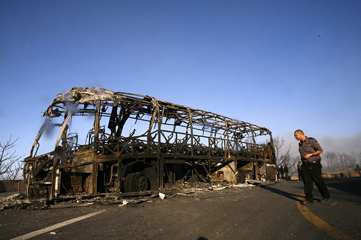 Israel Forest Fires: A firefighter walks next to the burnt-out bus near Beit Oren