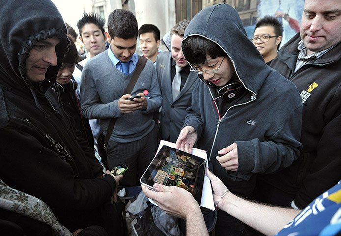 Year in business: Shoppers look at an iPad as they queue outside an Apple store in London