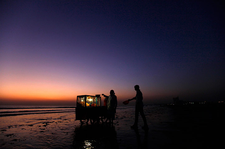 24 hours in pictures: A beach-goer goes to collect gol gappa from a vendor