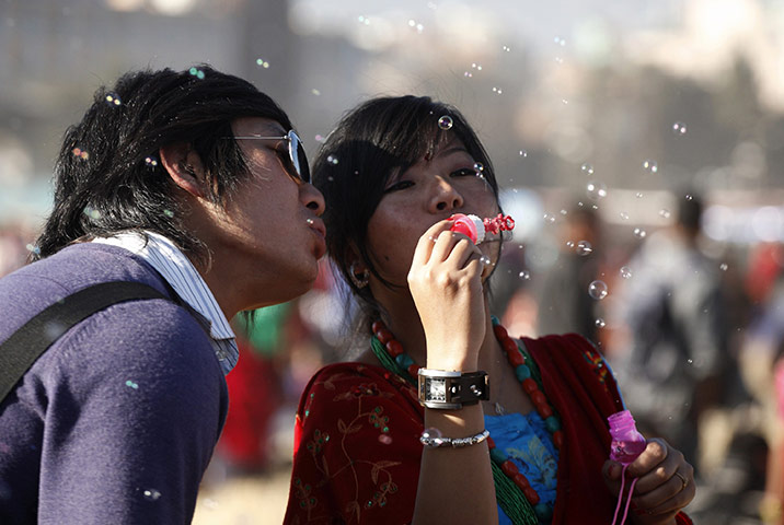 24 hours in pictures: Kathmandu, Nepal: A couple blow soap bubbles during the New Year parade