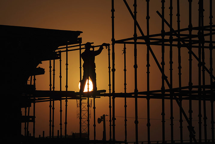 24 hours in pictures: Hefei, China: The sun rises as a labourer works on a railway viaduct