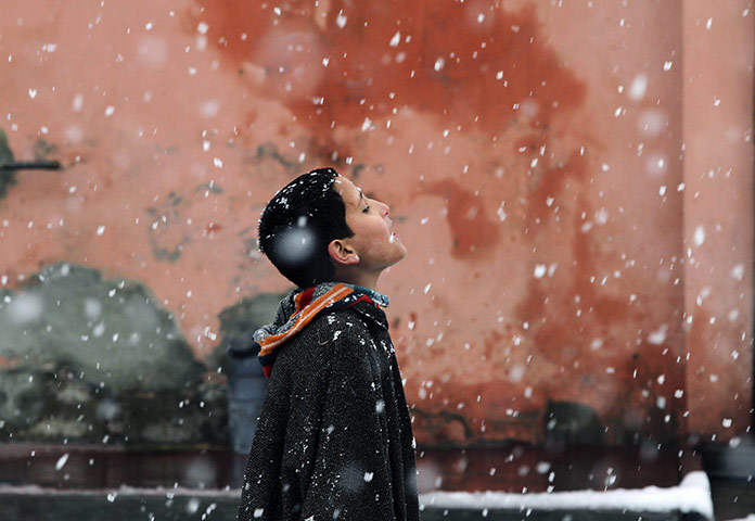 24 hours in pictures: Srinagar, India: A Kashmiri boy stands with his mouth open to eat snow