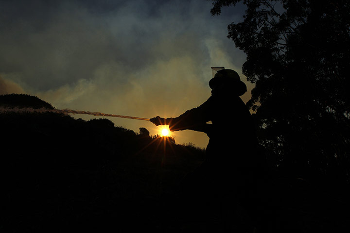 24 hours in pictures: Cape Town, South Africa: A firefighter douses flames on Signal Hill