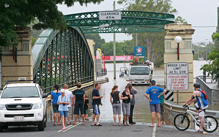Queensland Flooding: Residents gather at a flooded bridge leading into Bundaberg 