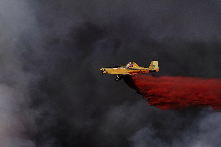 Israel forest fire: A plane sprays the retardant chemical on flames near village of Ussafiya