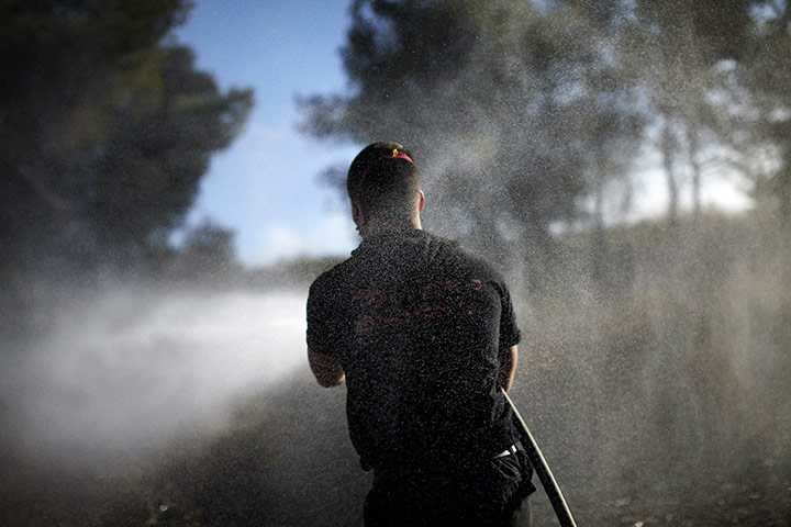 Israel forest fire: An Israeli firefighter douses a burning area in the village of Ussafiya
