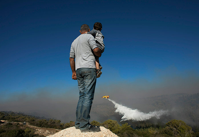 Israel forest fire: Locals watch a  firefighting plane spray fire extinguishing wildfir