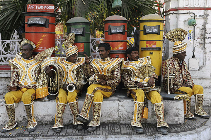 24 hours in pictures: Members of a wedding music band rest near letterboxes, India
