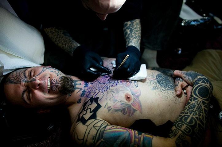 24 hours in pictures: An artist tattooes a client at the Berlin Tattoo Convention