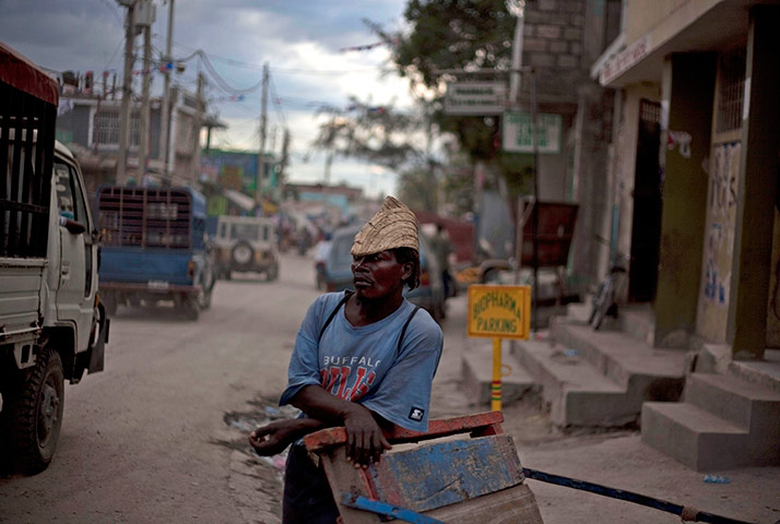 24 hours in pictures: A worker leans against a cart on a street in Port-au-Prince, Haiti