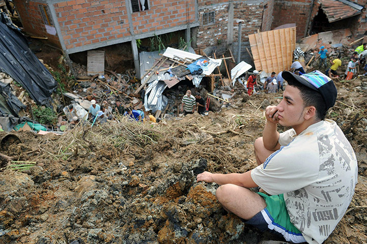 Floods: A youngster looks on as people remove rubble to find survivors 