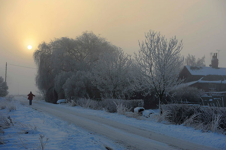 Snow and frost: A woman walks along a snow covered road in Humberton, northern England