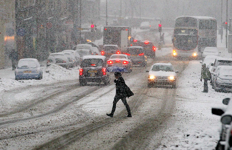 Snow and frost: A pedestrian crosses the street during snowfall in Edinburgh