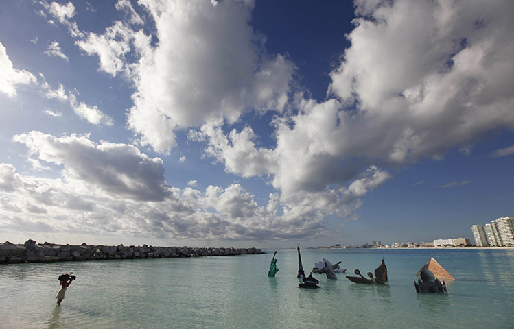 COP16 updates: Activists from Greenpeace demonstrate by holding images of landmarks in the water at Cancún