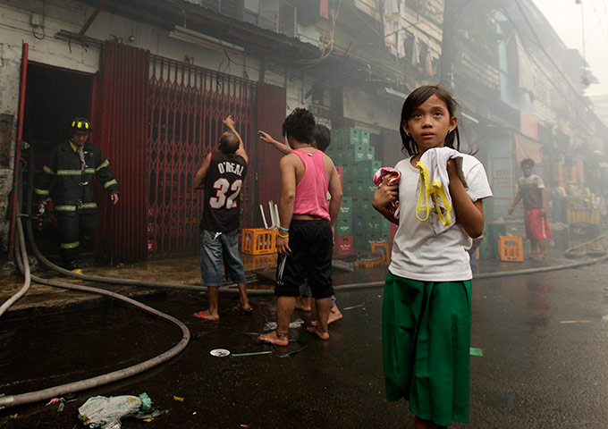 24 hours in pictures:  A Filipino resident flees during a fire in a slum community in Manil