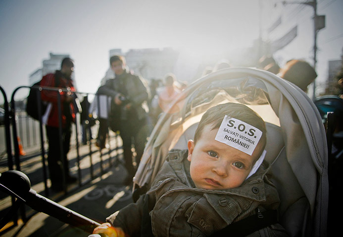24 hours in pictures: A baby looks on with a sticker that reads 'Save Romania's future'