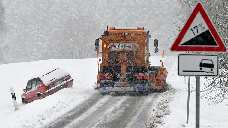 Cold weather abroad: Gemuenden, Germany: A snow plough passes an abandoned car t