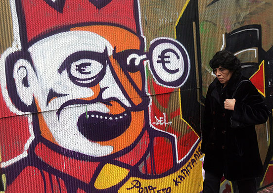 Greek strike: A woman walks by a graffiti Athens