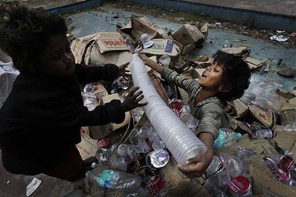 24 hours: A girl passes a stack of used plastic containers in New Delhi