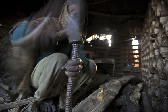 24 hours: A woman uses a hammer and metal spike to break a tree branch in Islamabad