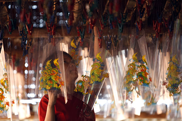 24 hours: A worker hangs decorative plastic for candlesin Indonesia